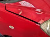 a close up of a red car that has a denting on it