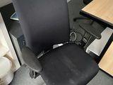 a black office chair sitting in front of a computer desk