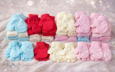 many pairs of baby mittens sitting on a blanket