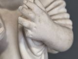 a small statue of a baby holding something in his hands
