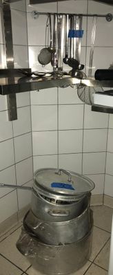 Dans une cuisine, des casseroles et des poêles sont suspendues au plafond.