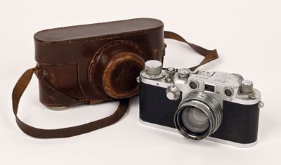 un appareil photo et un étui en cuir marron posés sur une surface blanche
