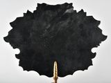 a black leaf shaped object with a gold tip on a table