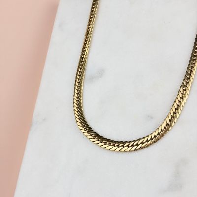 a close up of a gold chain necklace on a marble surface