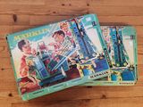 deux livres pour enfants posés sur une table en bois, avec une image de train en arrière-plan