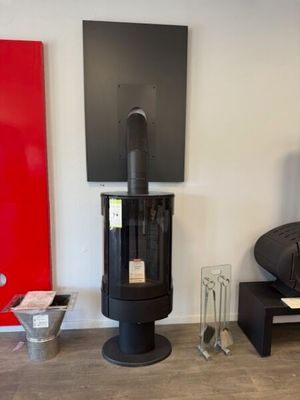 a black stove sitting in a living room next to a red wall