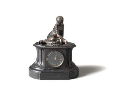 une petite statue représentant un garçon assis sur une horloge