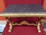 une petite table avec un plateau en marbre posée sur une chaise rouge