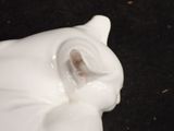 a white cat figurine sitting on a black surface