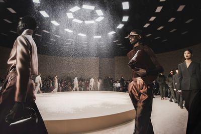 models walk down the runway at a fashion show in a dark room