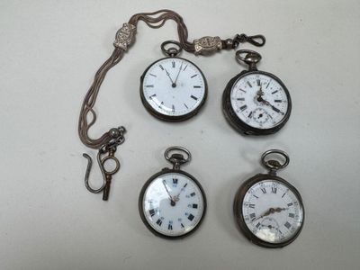four different types of pocket watches are displayed on a white surface