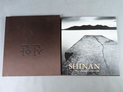 two books on a white table with a black and white photo of a rock