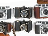 plusieurs vieux appareils photo sont alignés sur une surface blanche