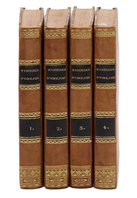 quatre livres sont alignés sur une surface blanche