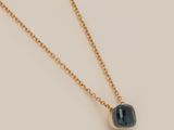 a gold necklace with a blue stone on a chain