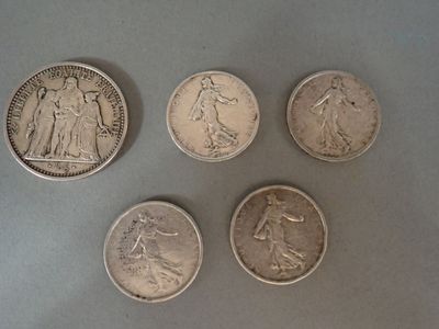 four different types of silver coins on a gray surface