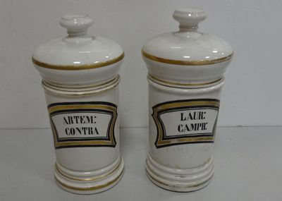 pair of white and gold ceramic jars with labels on them