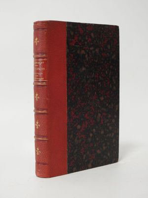an old book with a red cover sitting on top of a white surface