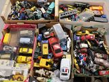 Des cartons remplis de petites voitures et de camions de toutes sortes sont posés par terre