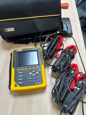 yellow and black electrical equipment sitting on a table next to a black bag