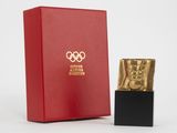 une boîte rouge avec une statuette dorée à côté