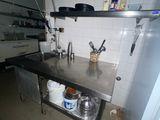une cuisine équipée d'un évier, d'une cuisinière et d'autres éléments posés sur le plan de travail