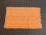 an orange piece of fabric sitting on top of a cutting mat