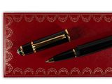 a black pen and a gold pen sitting on top of a red mat