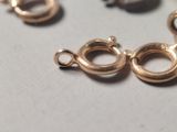three gold plated metal clasps on a white surface