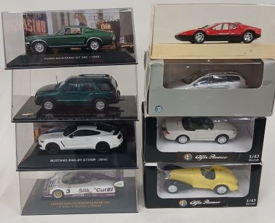 Quatre modèles différents de voitures sont exposés dans des vitrines posées sur une table