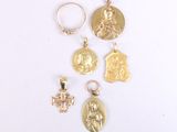 four gold - plated religious pendants on a white surface