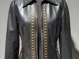une veste en cuir noir ornée de clous dorés, posée sur un mannequin
