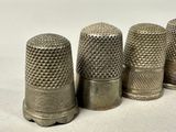 three antique thimbles lined up in a row on a white surface