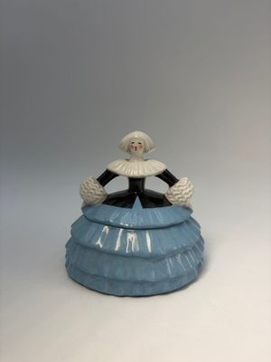 a figurine of a woman in a blue dress sitting on top of a cake