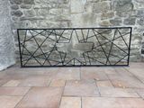 a black iron fence on a brick floor next to a stone wall