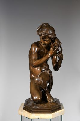 bronze statue of a boy holding a bird on a pedestal