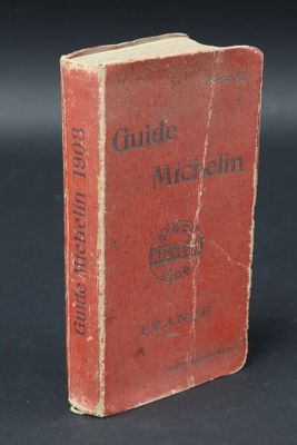 an old red book sitting on top of a table next to a black background