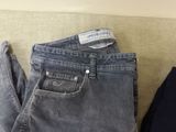 two pairs of grey jeans sitting on top of a couch next to each other