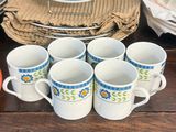 several cups and saucers are sitting on a table with plates and napkins