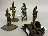 quatre figurines en bronze de tailles et de formes différentes posées sur une surface blanche
