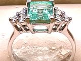 une image d'une bague avec une pierre verte entourée de diamants