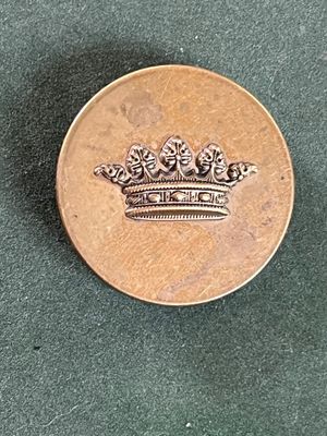 une pièce de monnaie sur laquelle est représentée une couronne, posée sur une table