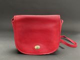 a red leather cross body bag with a gold clasp