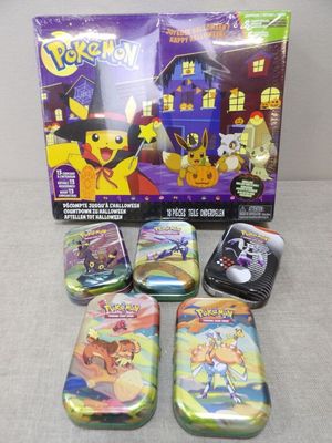 the pokemon tins are lined up on the table in front of the box