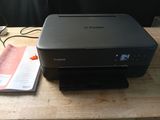 a canon printer sitting on a desk next to a book