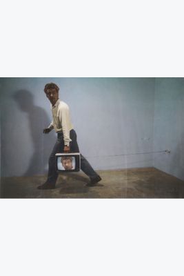 a man that is walking with a television in his hand