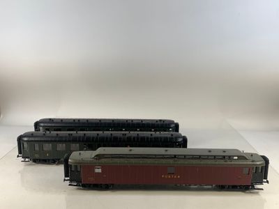 trois trains miniatures sont alignés sur une surface blanche
