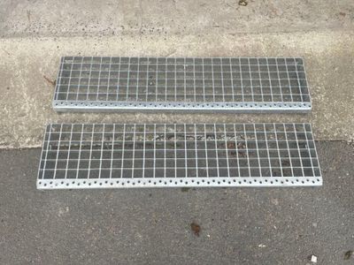 two metal grates laying on the ground next to a sidewalk