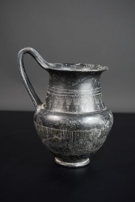 un vieux vase en argent posé sur une table noire