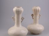 two white vases with handles on each of them